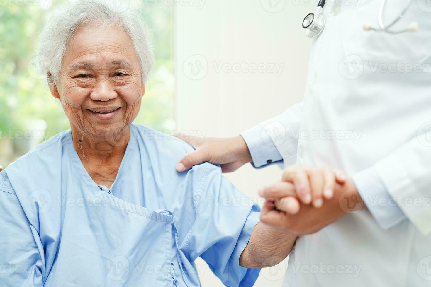 médico tomados de la mano paciente anciana asiática, ayuda y atención en el hospital. foto