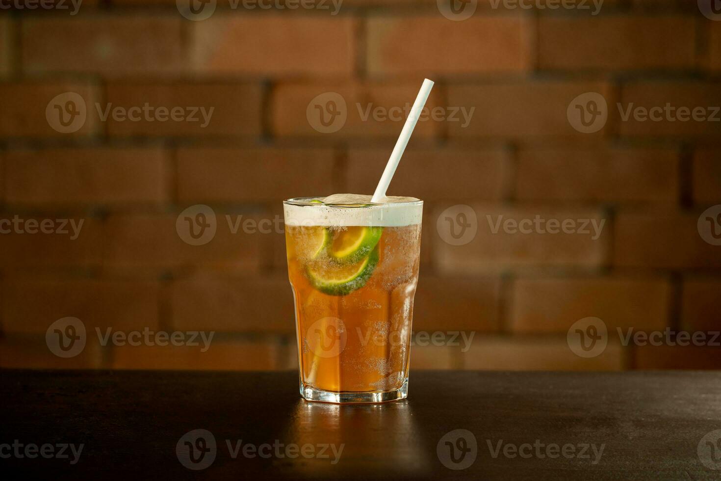 Glass of lime caipirinha drink on a table in front of a brick wall with space for text photo