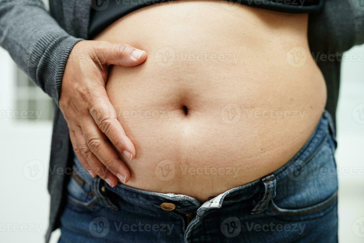 Asian woman show fat belly big size overweight and obesity at office. photo
