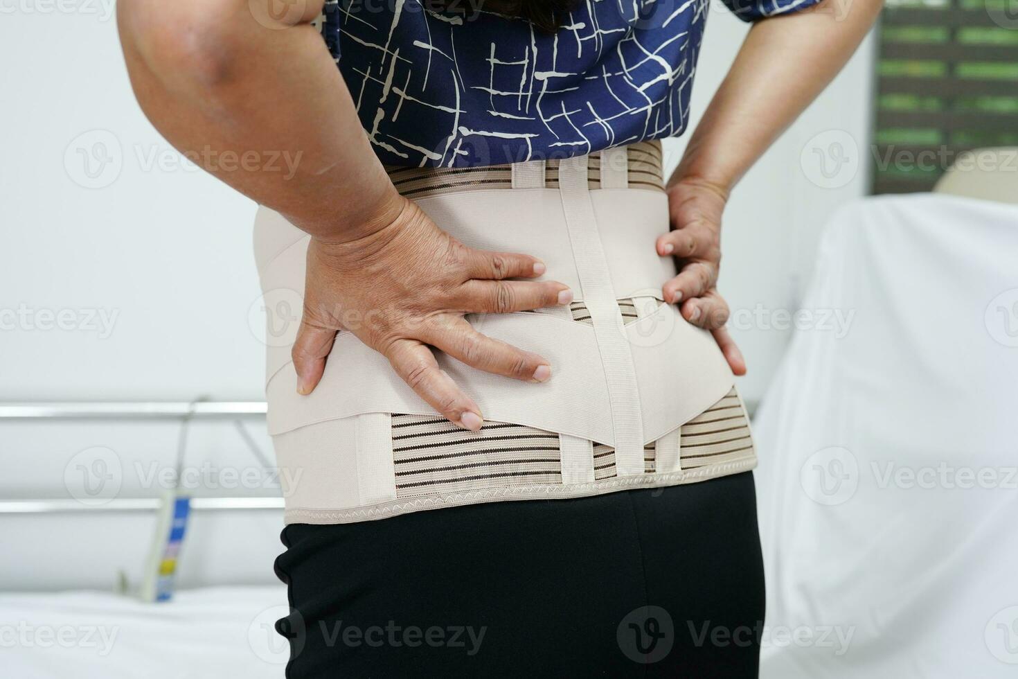 Asian senior wearing elastic support belt can help reduce back pain