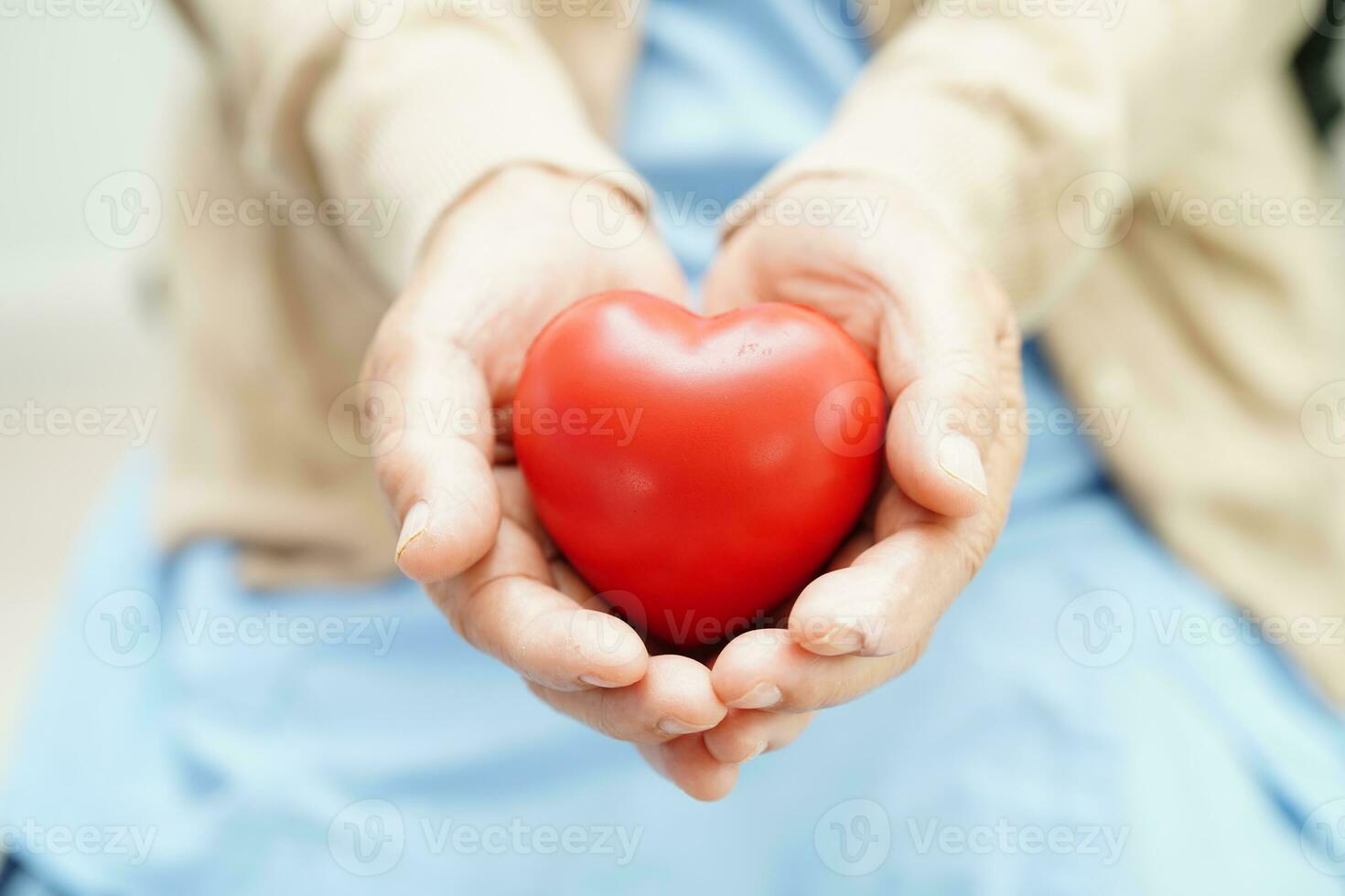 Asian elder senior woman patient holding red heart in hospital. photo