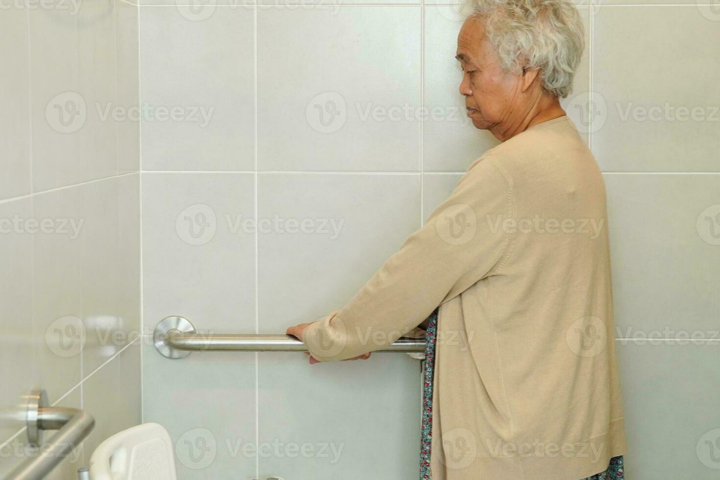 Asian elderly old woman patient use toilet support rail in bathroom, handrail safety grab bar, security in nursing hospital. photo