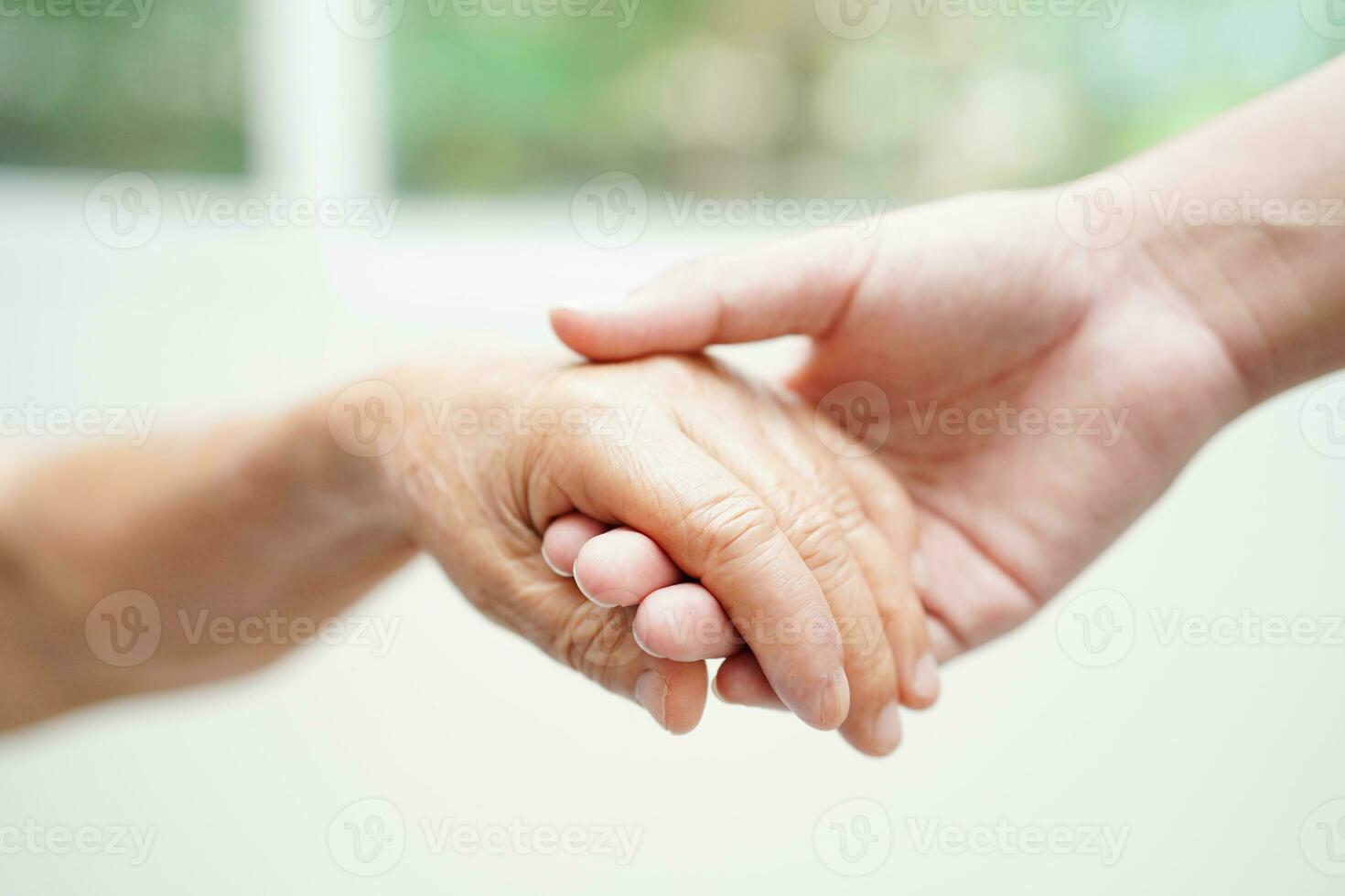 Asian young boy holding old grandmother woman hand together with love and care. photo