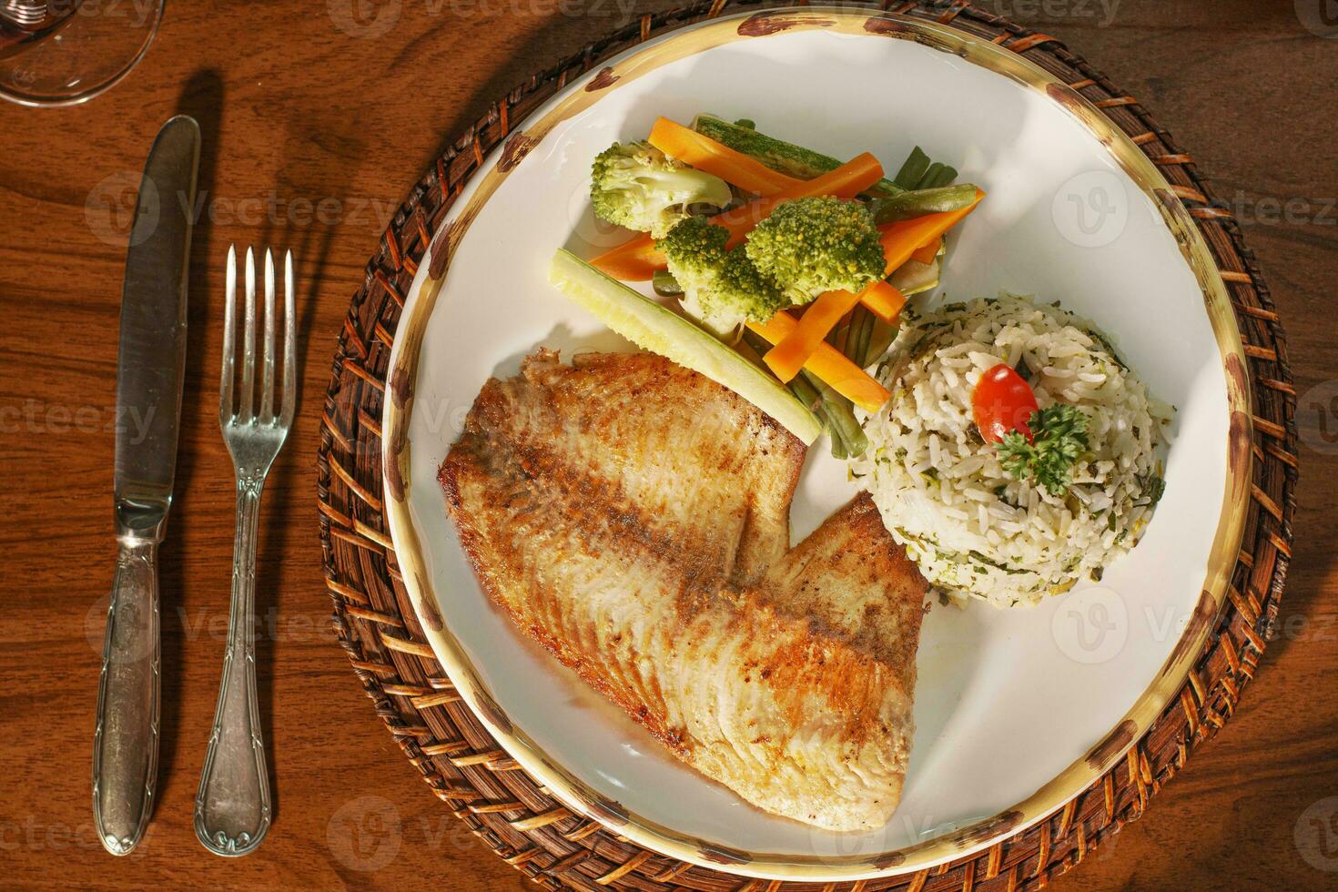 Beautiful plate of grilled fish with rice. In the background old books photo
