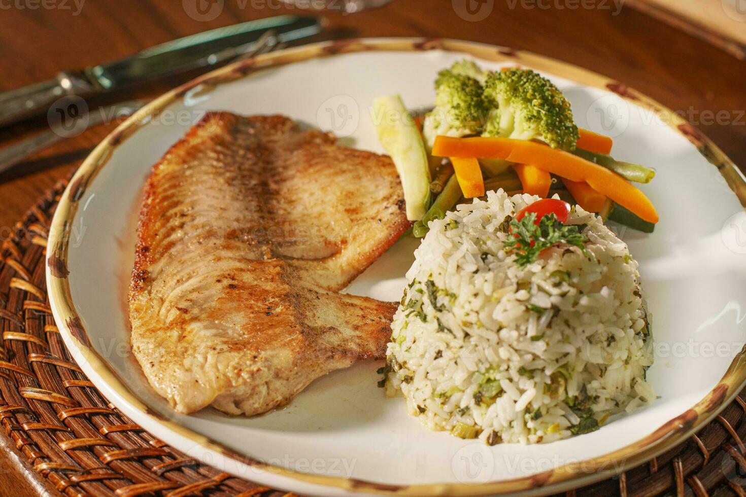 Beautiful plate of grilled fish with rice. In the background old books photo