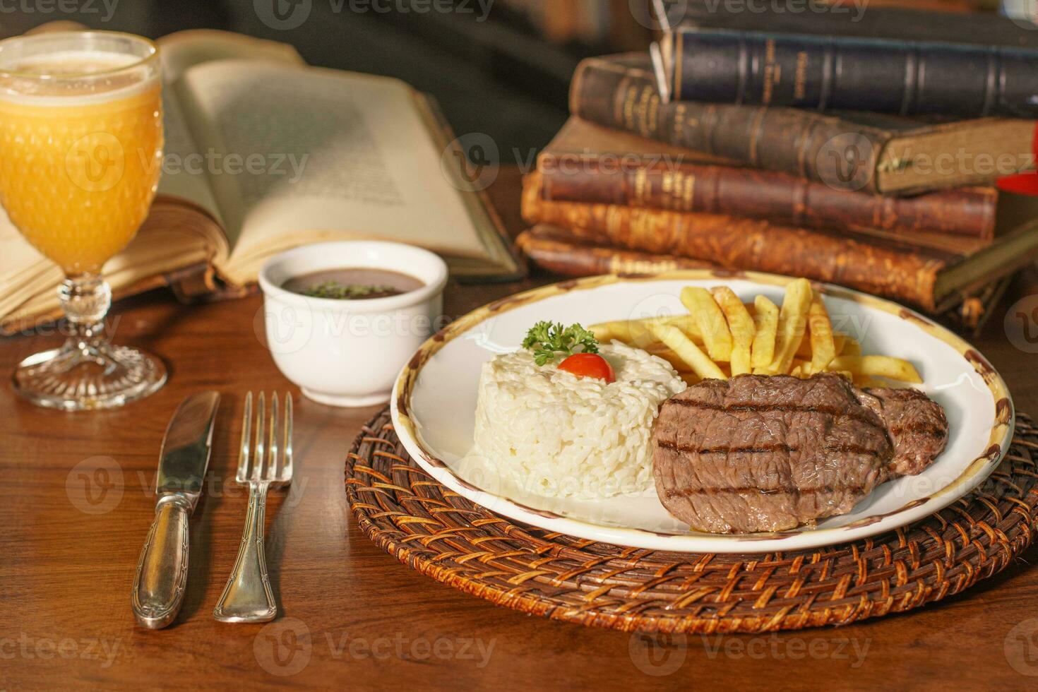 Beautiful dish of rice, beans and grilled meat. In the background old books photo
