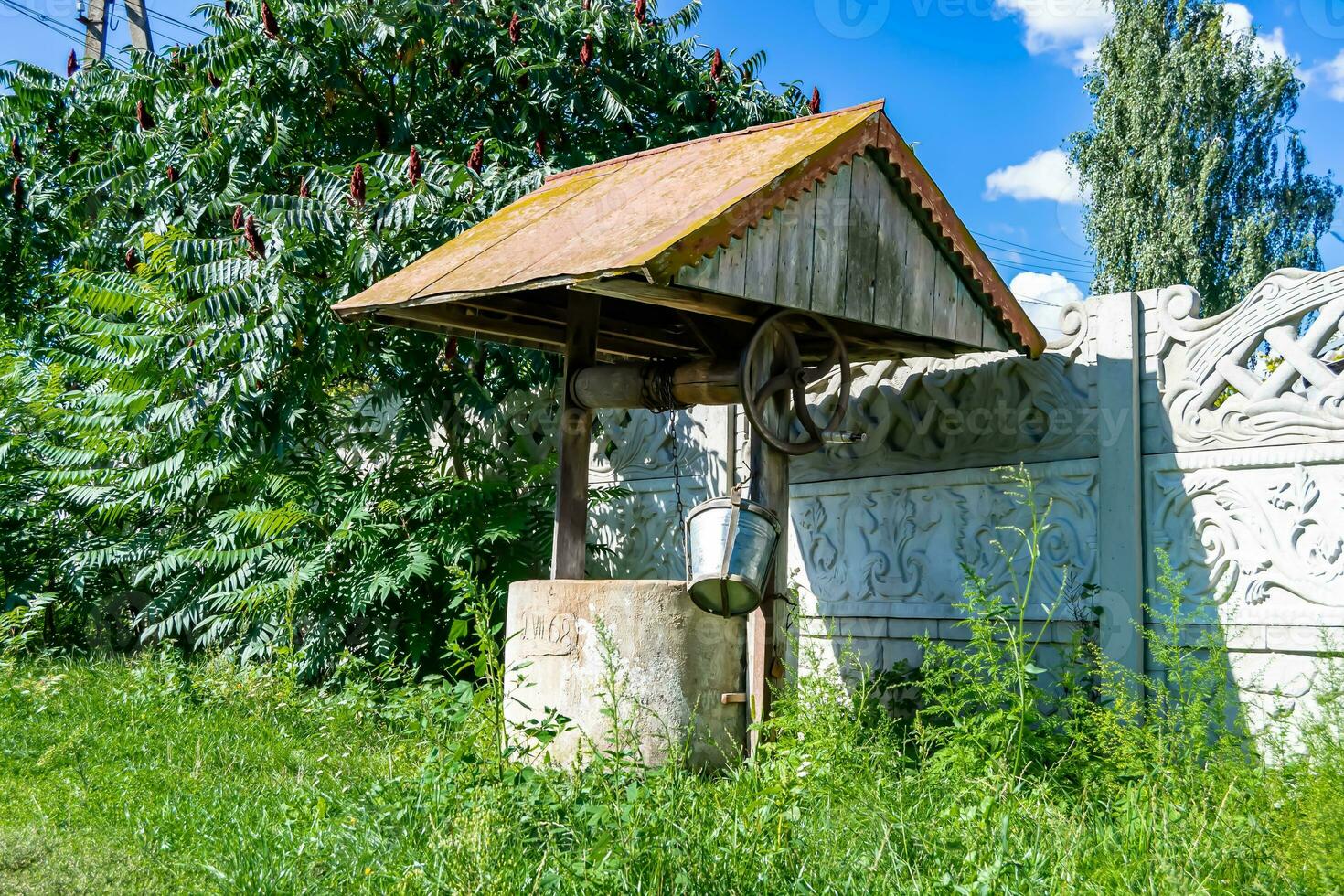 Old well with iron bucket on long forged chain for clean drinking water photo