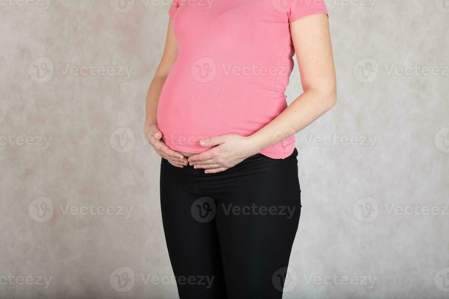 joven embarazada mujer mantiene su manos a el barriga. foto