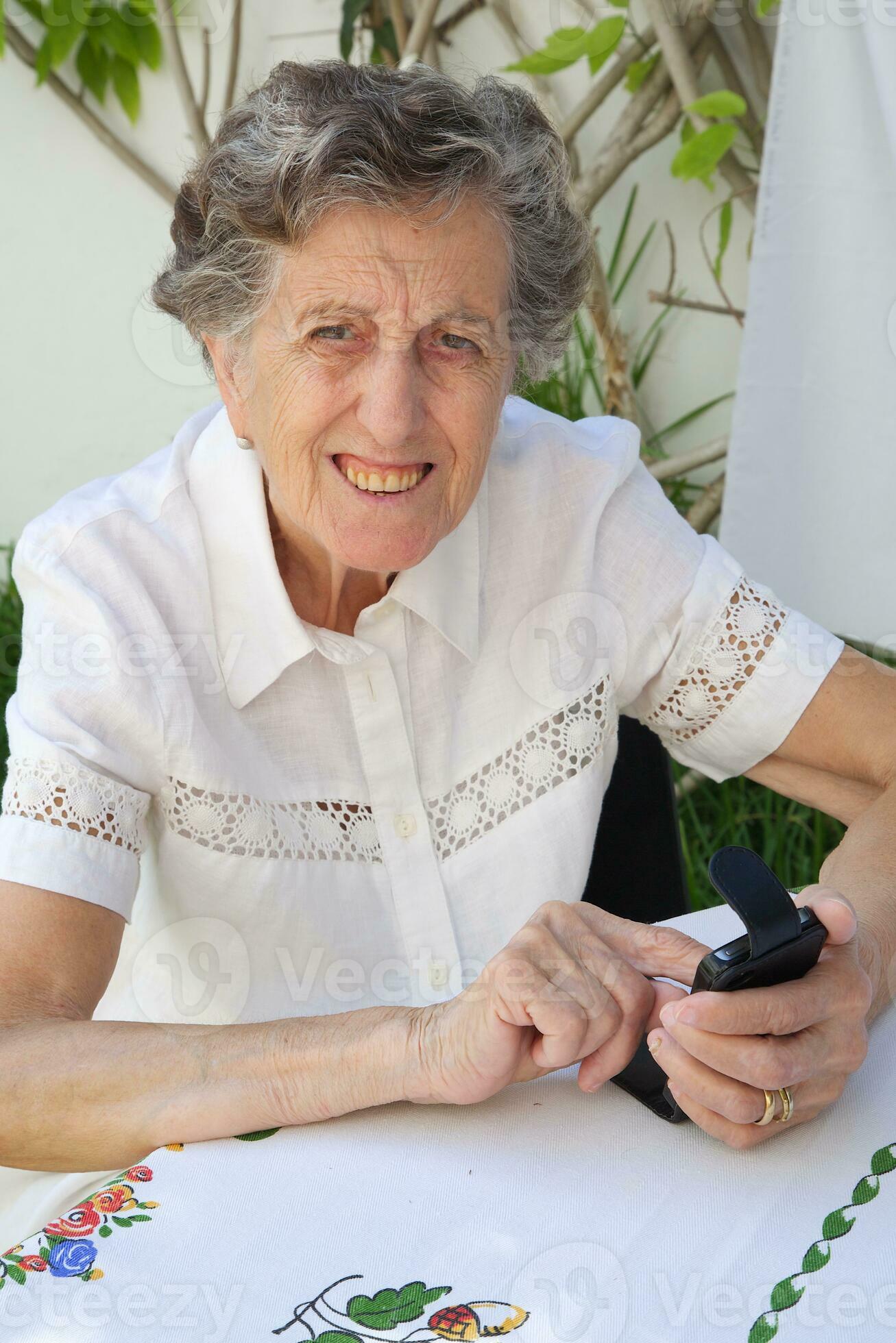 An Old Woman Is Dialling Up A Telephone Number On Her Smartphone an-old-woman-is-dialling-up-a-telephone-number-on-her-smartphone