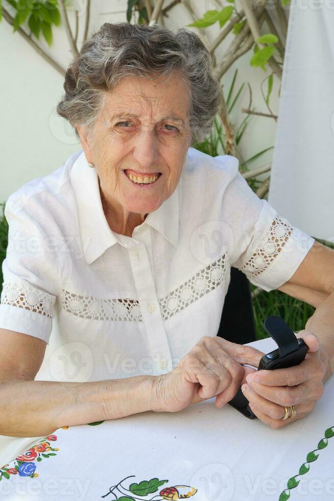 An old woman is dialling up a telephone number on her smartphone photo