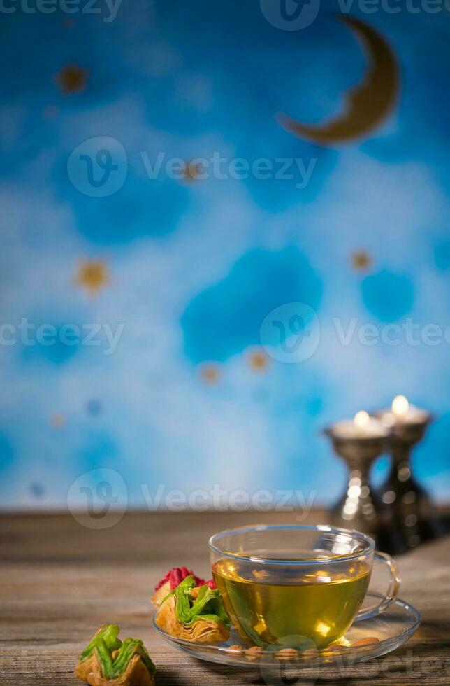 Tea in a glass cup with Arabic sweets on a wooden surface. photo