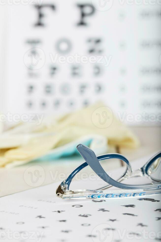 Eyeglasses for children on a eye chart close to eye pads. photo