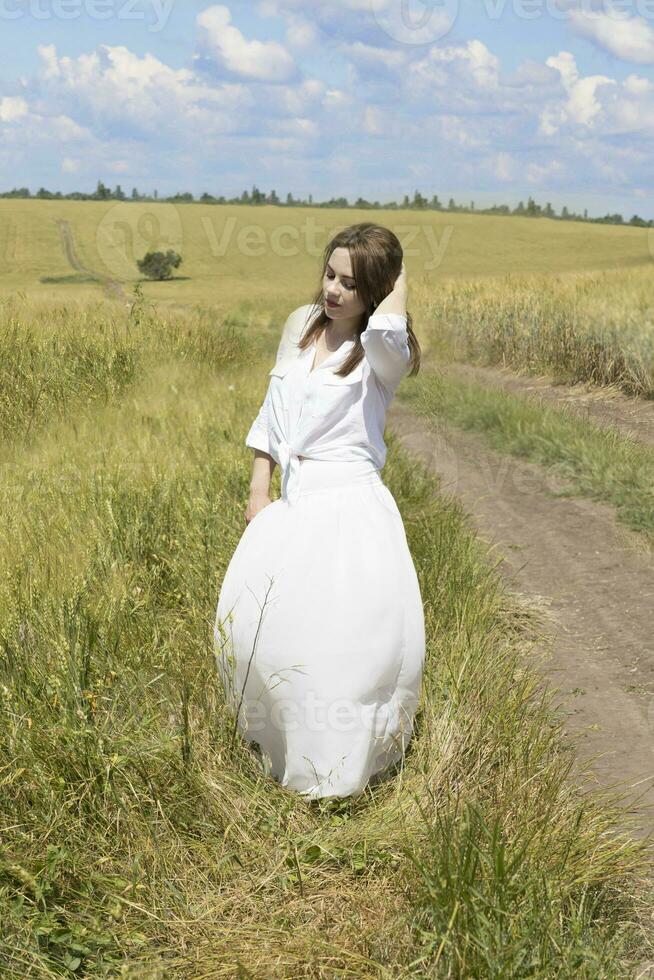 Young caucasian lady stays in wheat field photo