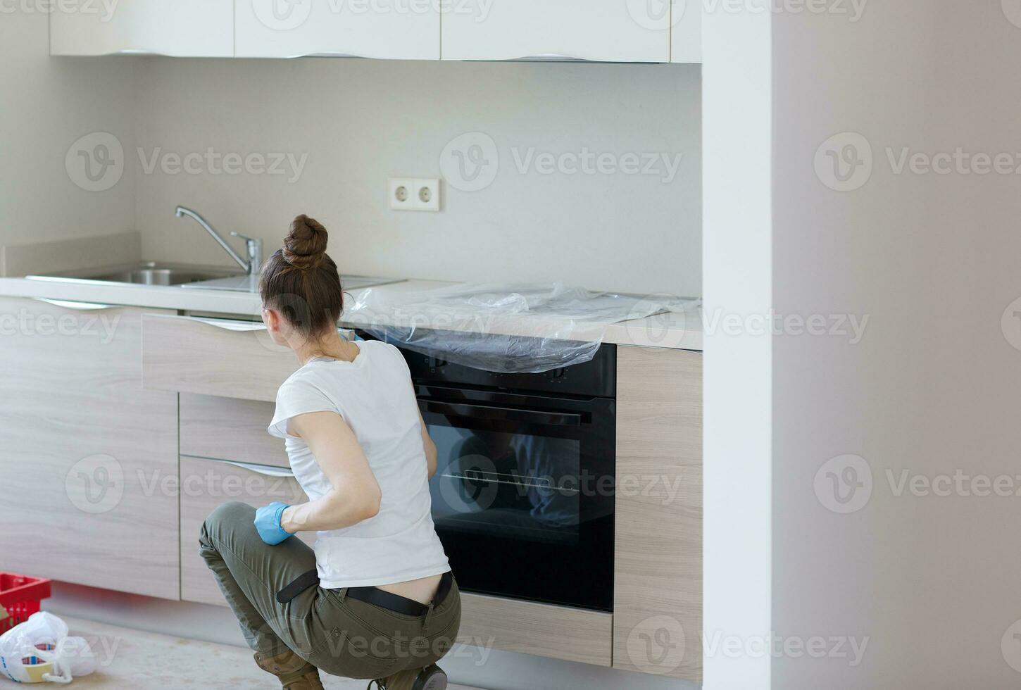 Young lady stays in front newly installed kitchen photo