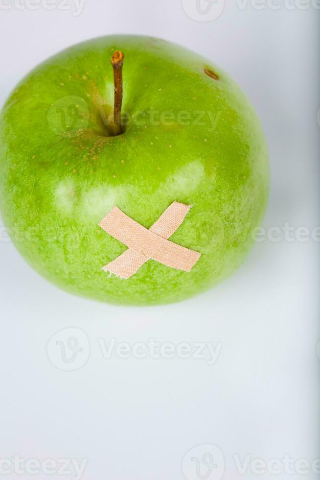 Green apple with healing plaster on it. Closeup photo
