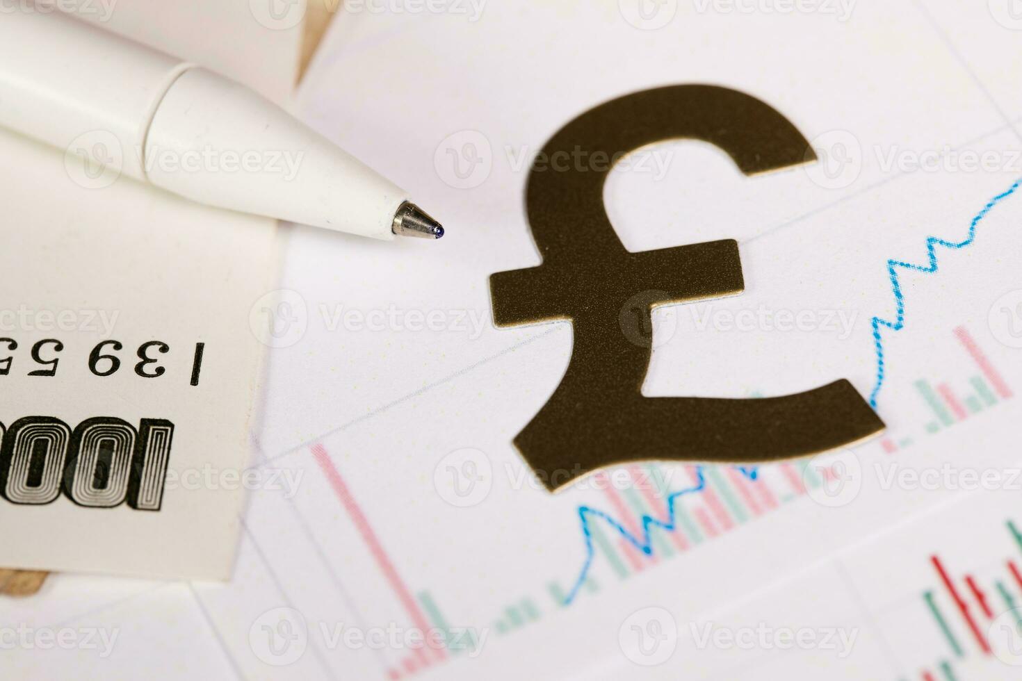 Pen on a banknote. Cutout of British pound sign in the background. photo