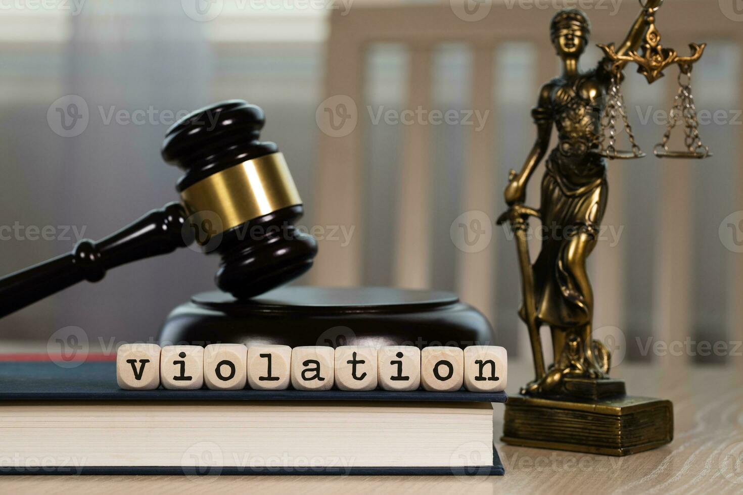 Word VIOLATION composed of wooden dices. Wooden gavel and statue of Themis in the background. photo