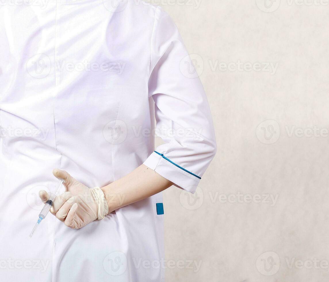 un médico vestido en un profesional uniforme se esconde jeringuilla con medicación foto