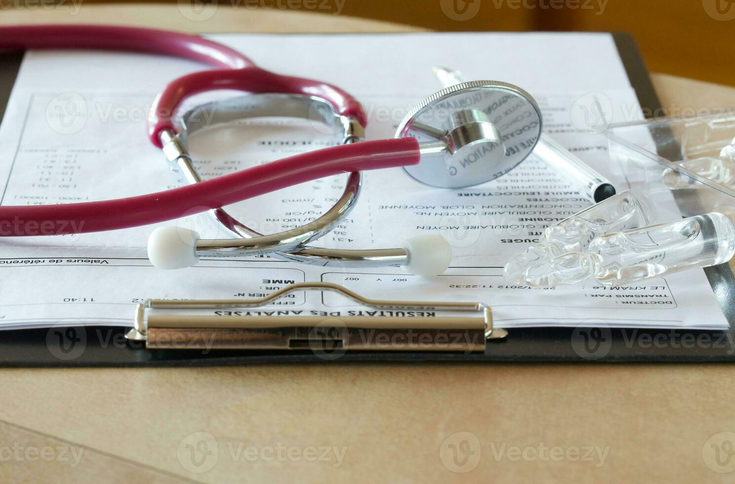 Stethoscope and results of blood analysis in French on a doctors table. Closeup photo