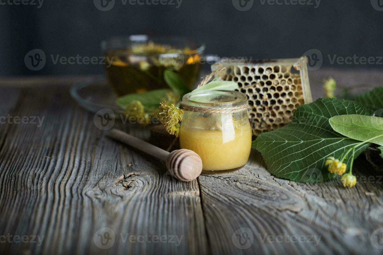 tilo flores miel en un vaso botella en un de madera superficie. foto