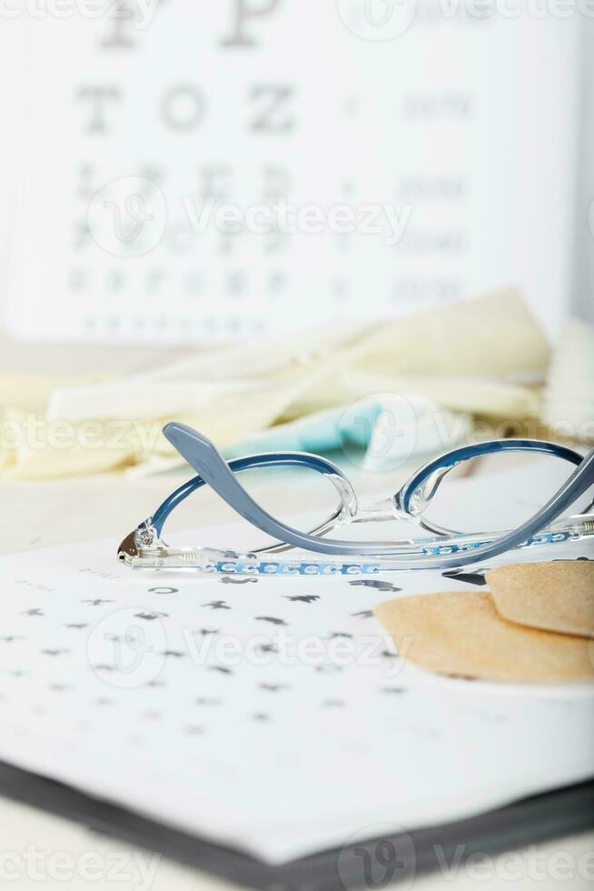 Eyeglasses for children on a eye chart close to eye pads. photo