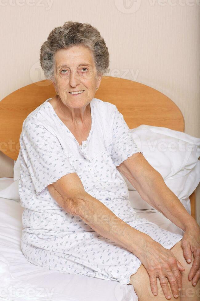 Senior woman is sitting in her bed photo