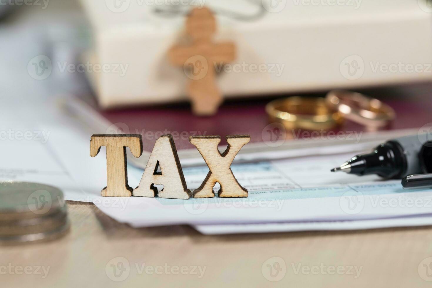 Word TAX composed of wooden letters in front of marriage golden rings. photo