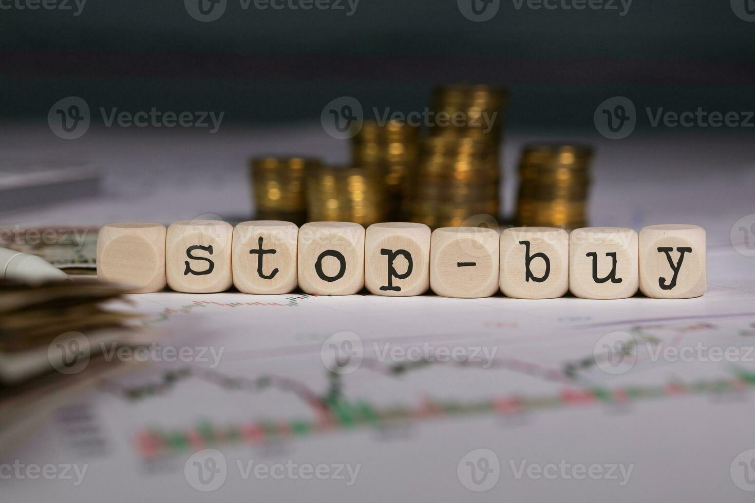 Word STOP-BUY composed of wooden letter. Stacks of coins in the background. photo