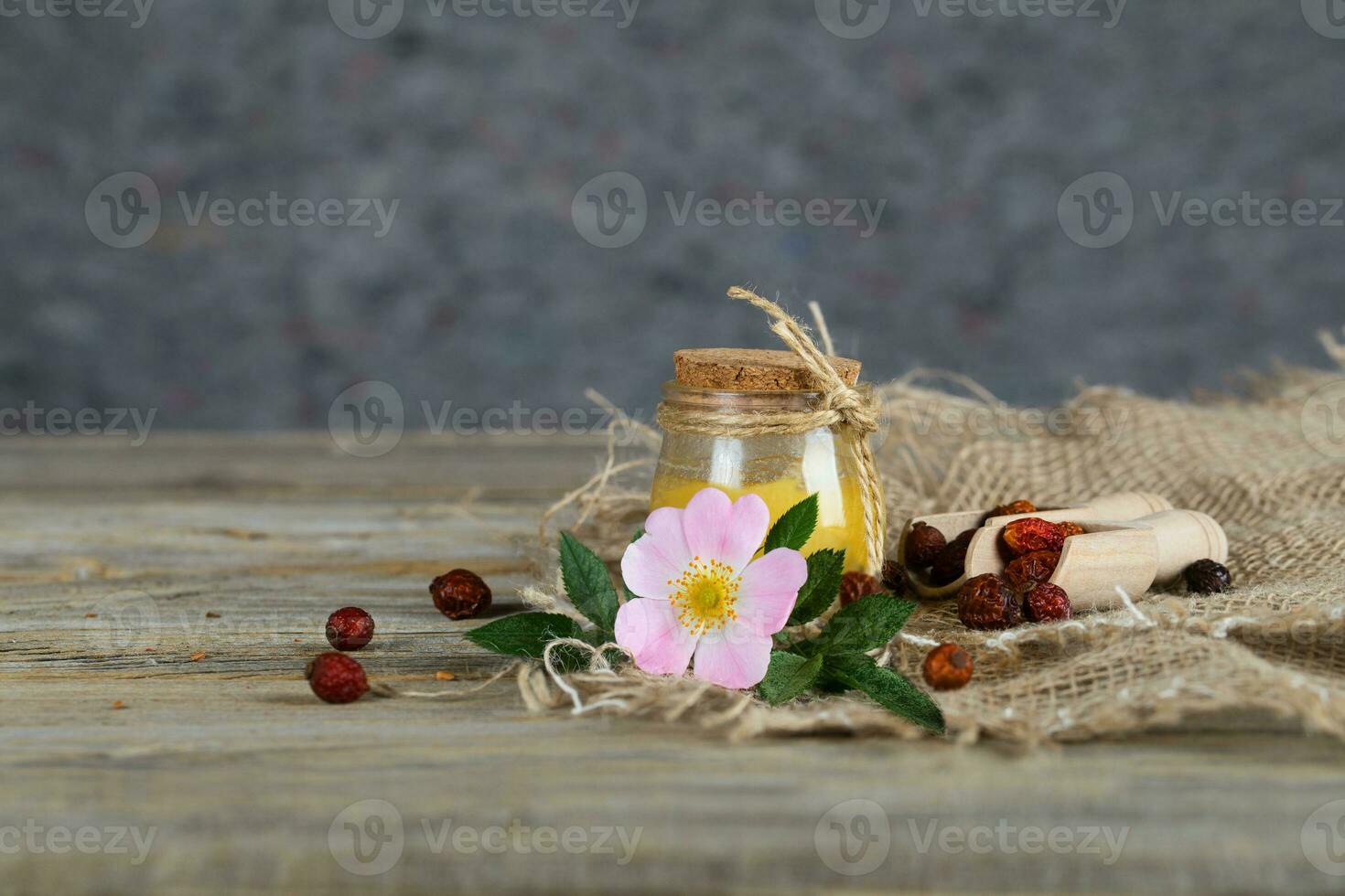 Wild rose hip honey in a glass bottle on a wooden surface. photo