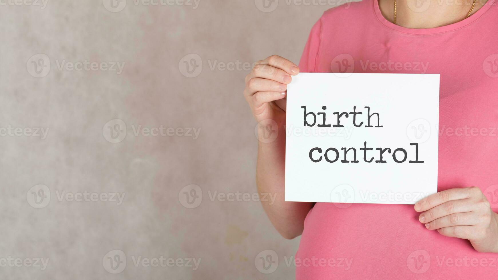 Young pregnant between 30 and 35 years old woman keeps white sheet of paper with words BIRTH CONTROL. photo