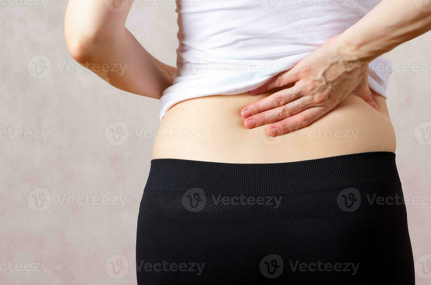 Young caucasian lady has a pain in her back Closeup photo