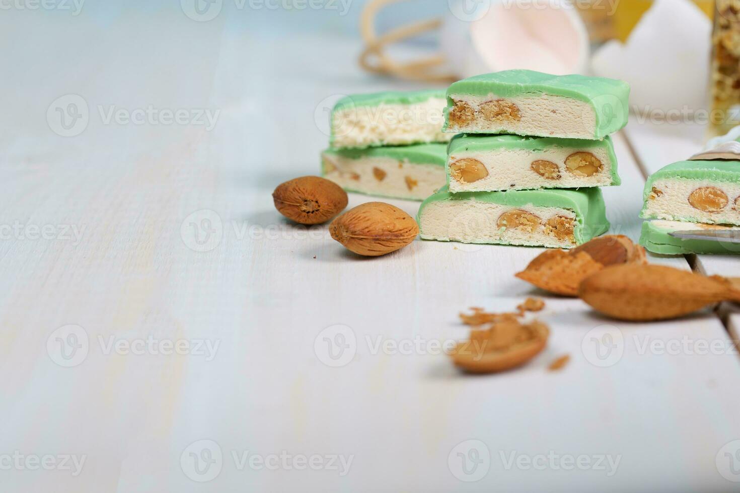 Almond turron covered by pistachio chocolate on a wooden surface. photo