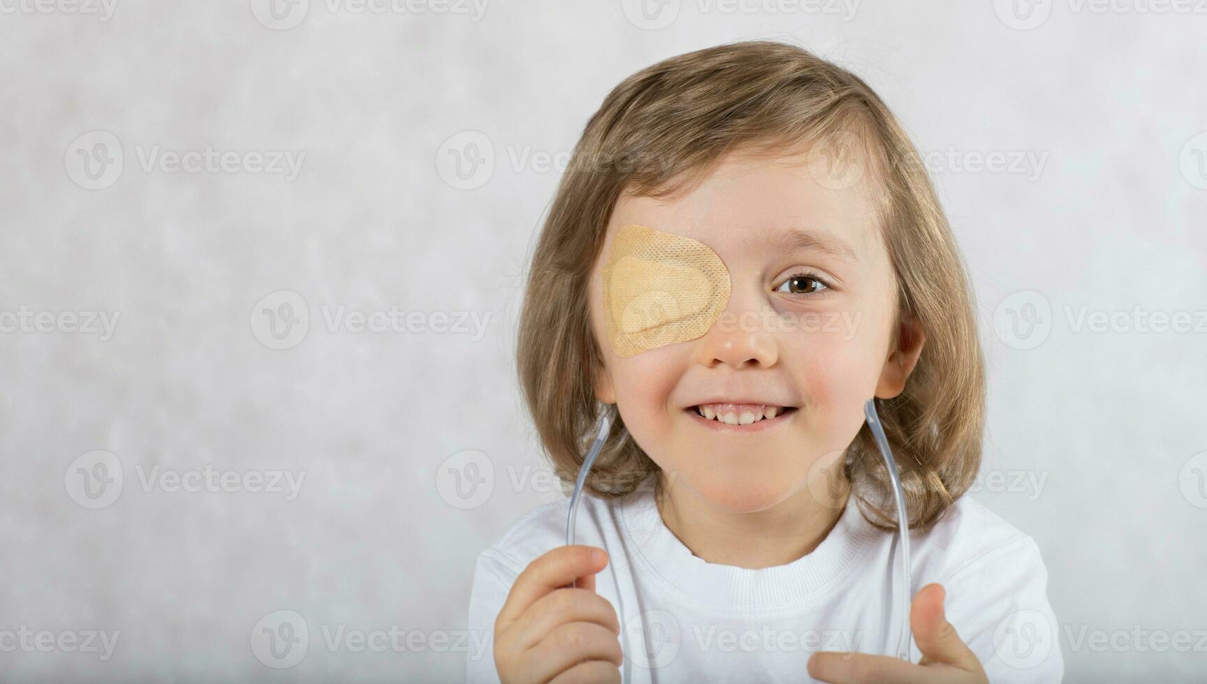 Boy with one eye covered by eye pad and with eye glasses. photo