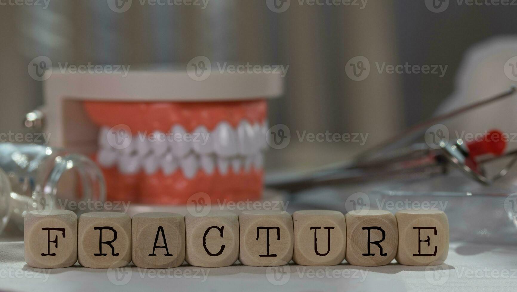 Word FRACTURE composed of wooden dices. Pills, documents, pen, human jaw model in the background. photo