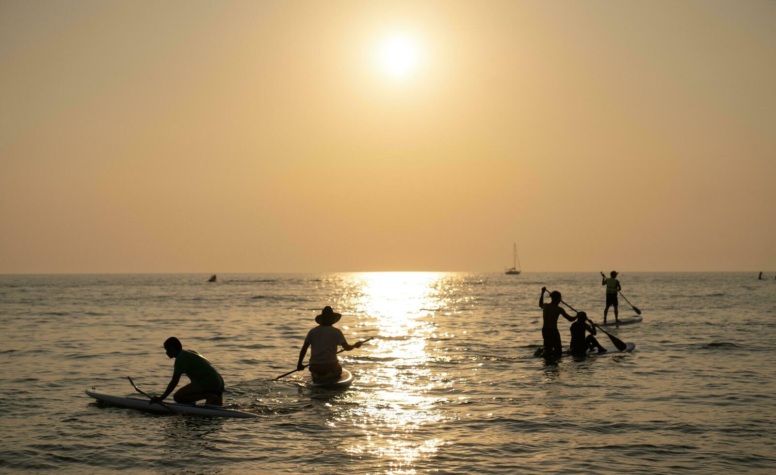 junio 21, 2021. Pattaya tailandia grupo de personas en estar arriba paleta tablero a tranquilo mar en puesta de sol o amanecer. y brillante puesta de sol foto