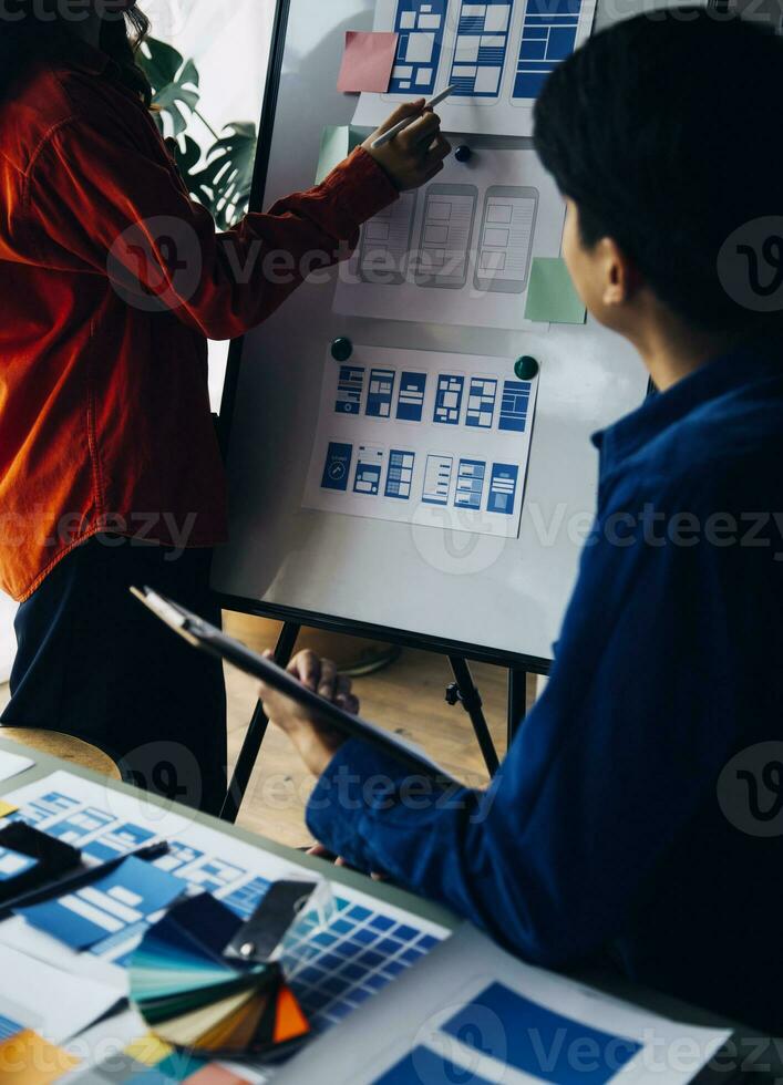 Close up ux developer and ui designer brainstorming about mobile app interface wireframe design on table with customer breif and color code at modern office.Creative digital development agency photo