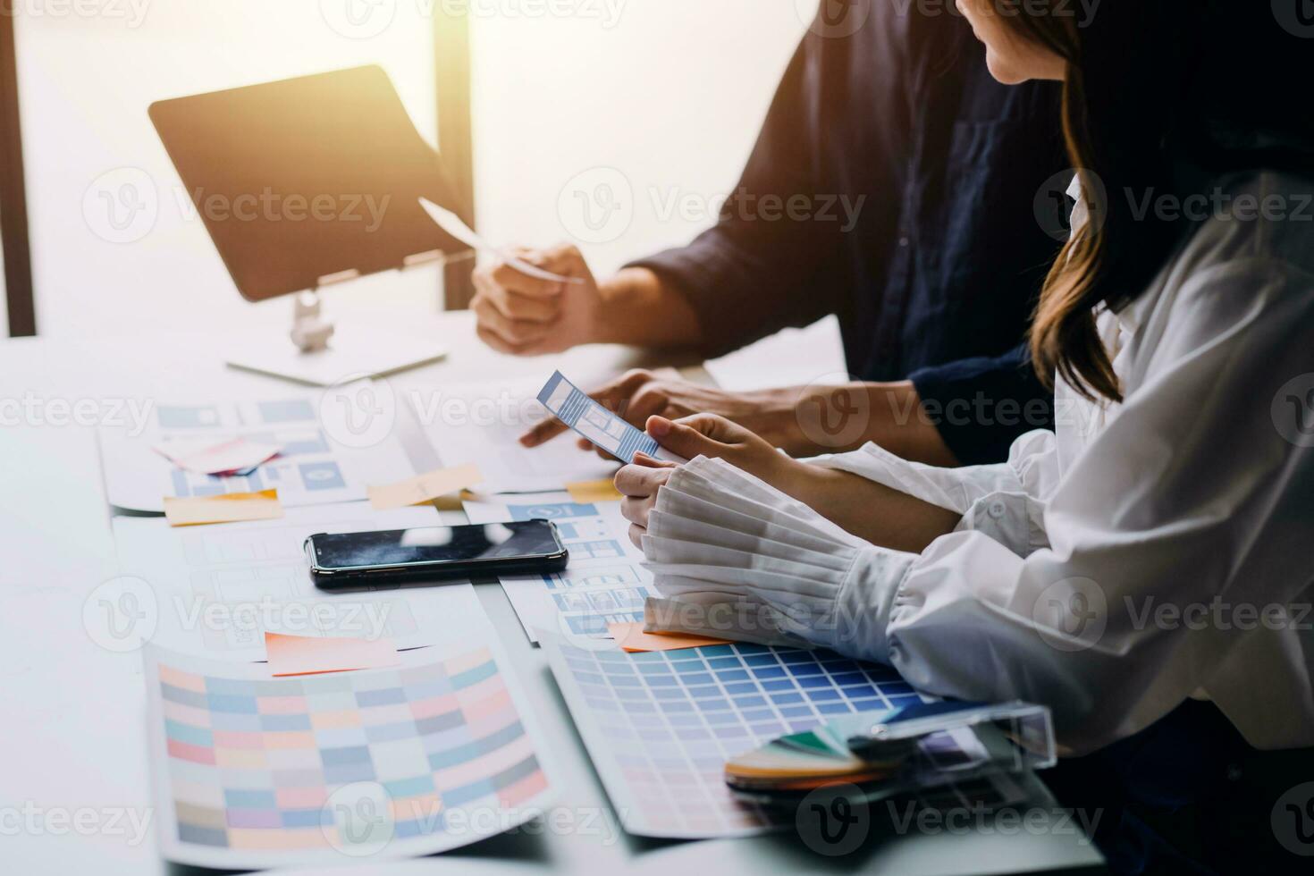 Close up ux developer and ui designer brainstorming about mobile app interface wireframe design on table with customer breif and color code at modern office.Creative digital development agency photo