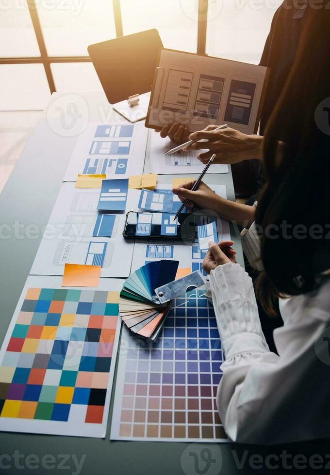 Close up ux developer and ui designer brainstorming about mobile app interface wireframe design on table with customer breif and color code at modern office.Creative digital development agency photo