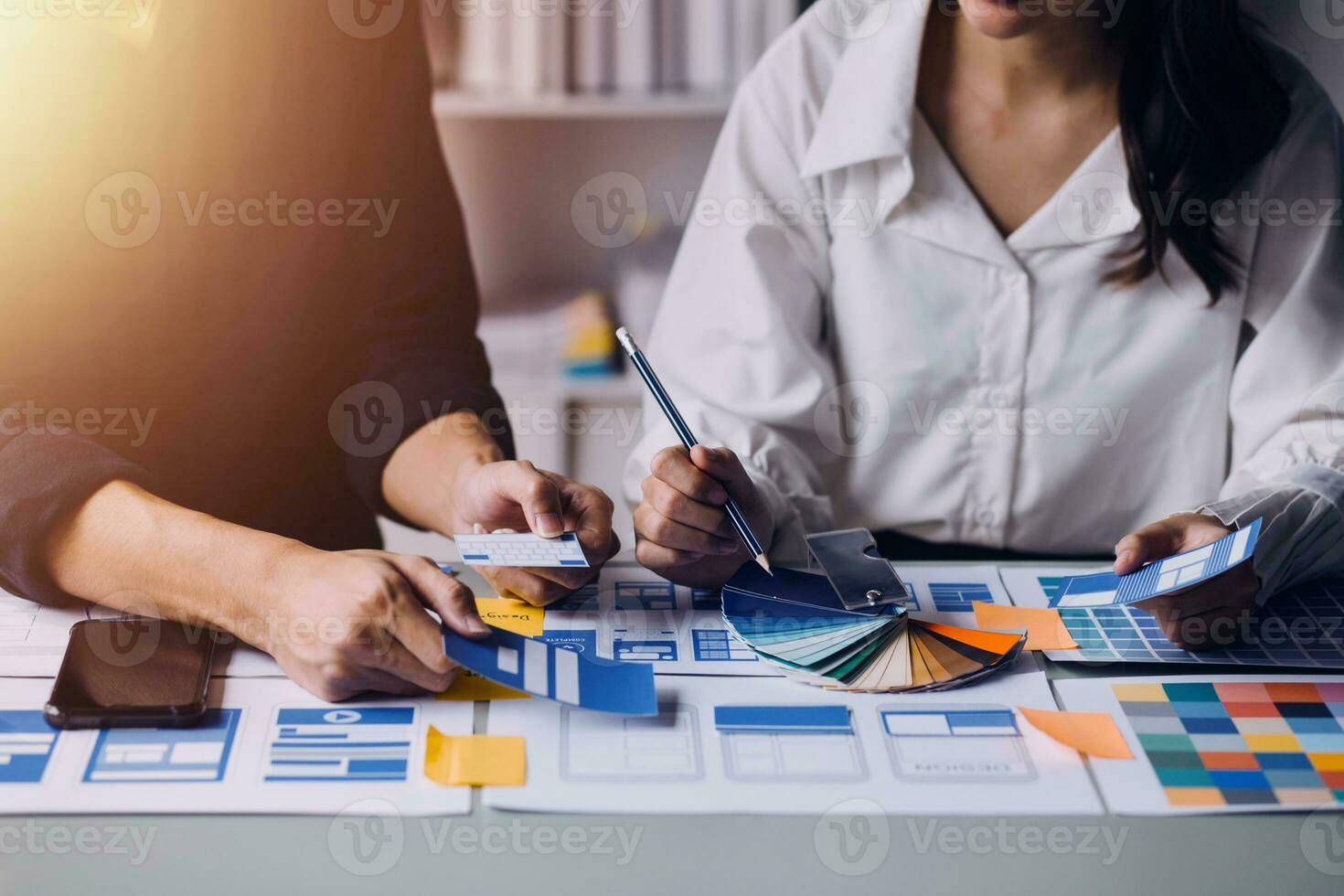 Close up ux developer and ui designer brainstorming about mobile app interface wireframe design on table with customer breif and color code at modern office.Creative digital development agency photo