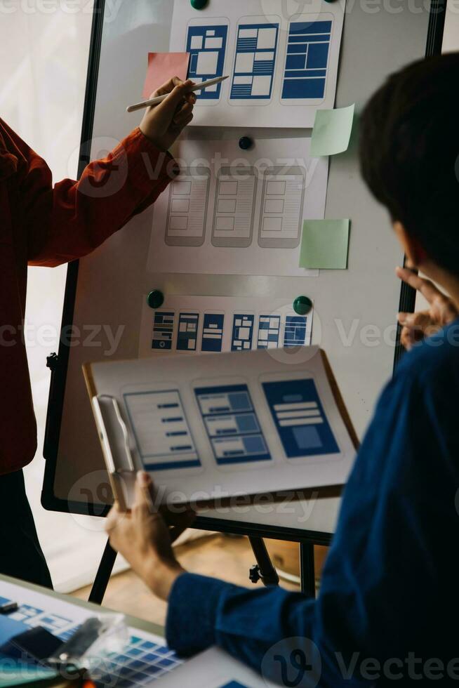 Close up ux developer and ui designer brainstorming about mobile app interface wireframe design on table with customer breif and color code at modern office.Creative digital development agency photo