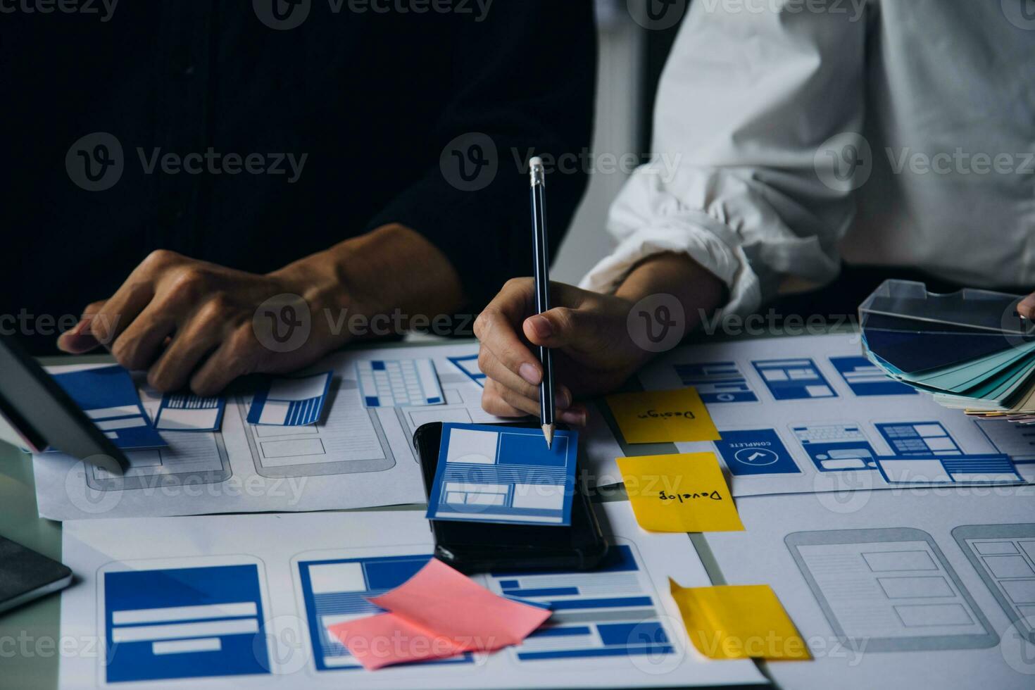 Close up ux developer and ui designer brainstorming about mobile app interface wireframe design on table with customer breif and color code at modern office.Creative digital development agency photo