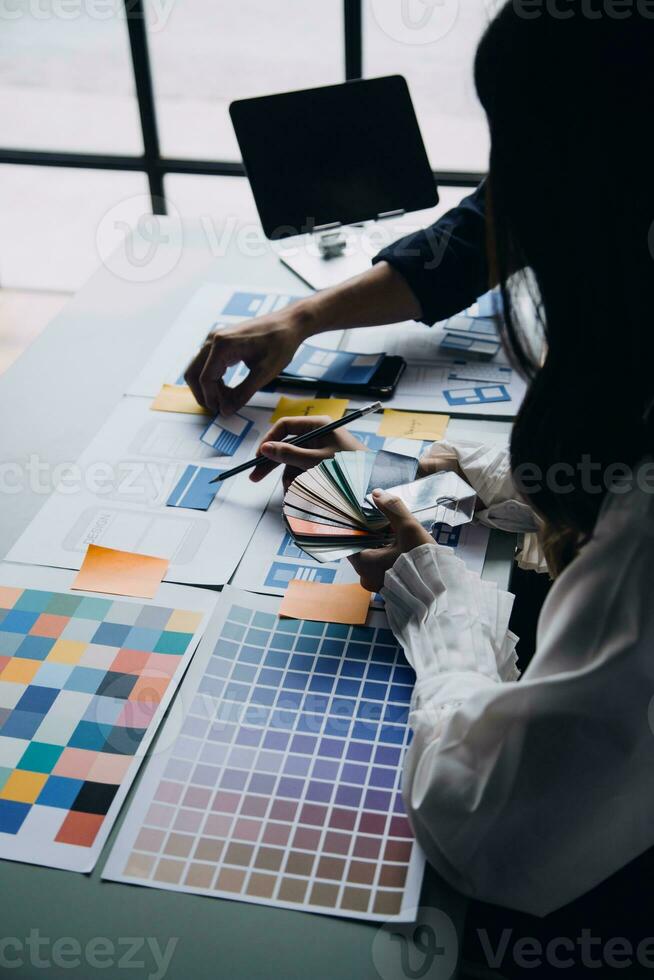 Close up ux developer and ui designer brainstorming about mobile app interface wireframe design on table with customer breif and color code at modern office.Creative digital development agency photo
