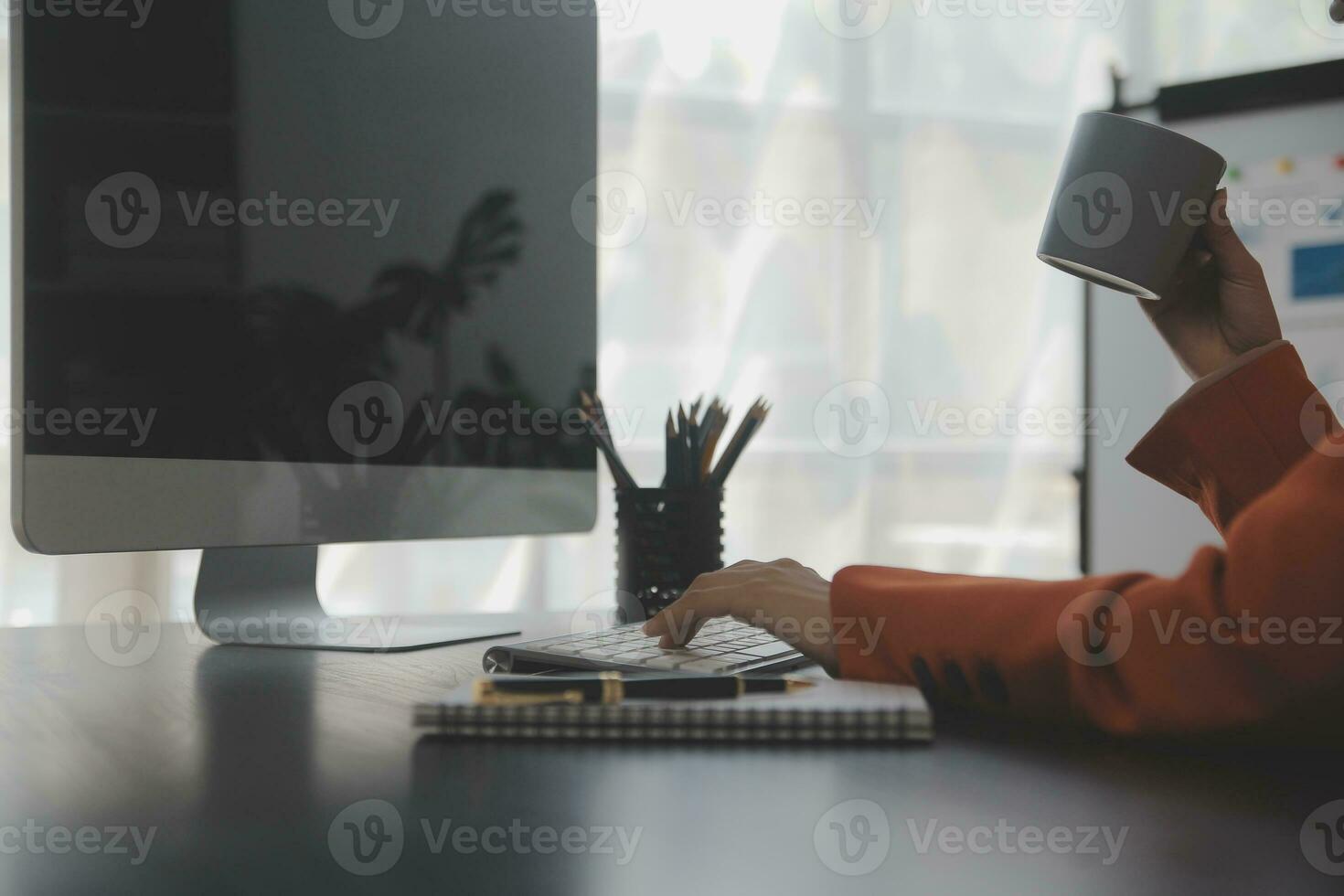 Asian Business woman using calculator and laptop for doing math finance on an office desk, tax, report, accounting, statistics, and analytical research concept photo