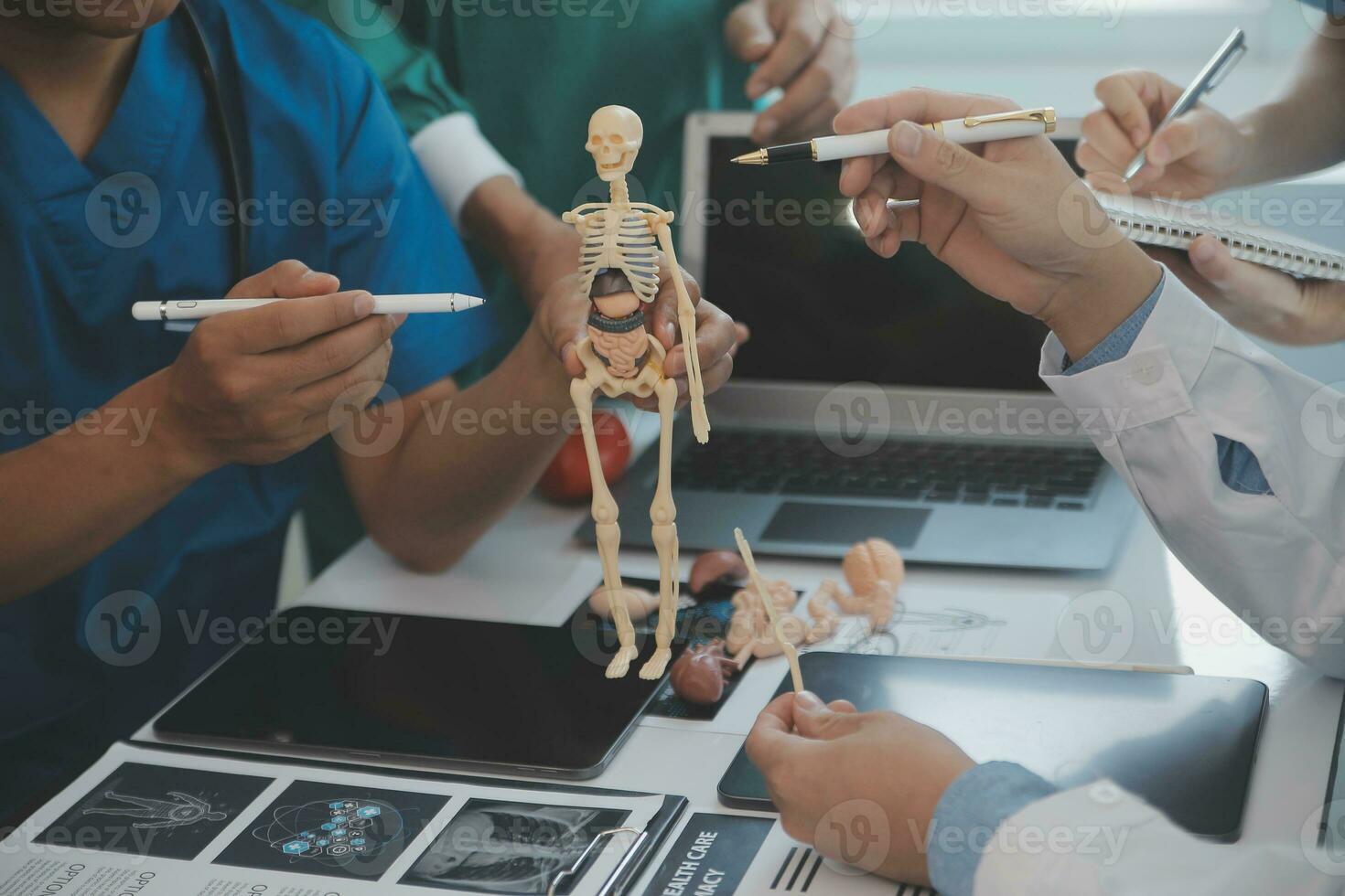 Multiracial team of doctors discussing a patient standing grouped in the foyer looking at a tablet computer, close up view photo