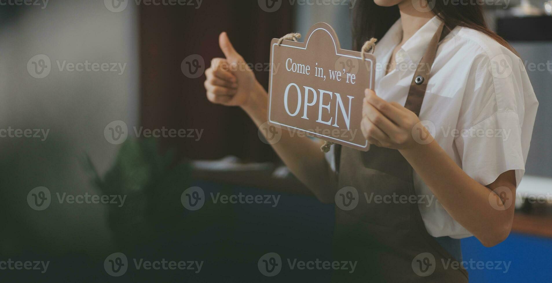 Young entrepreneur holding open sign on glass door at cafe photo