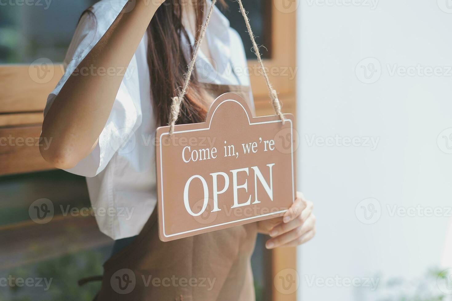 Young entrepreneur holding open sign on glass door at cafe photo
