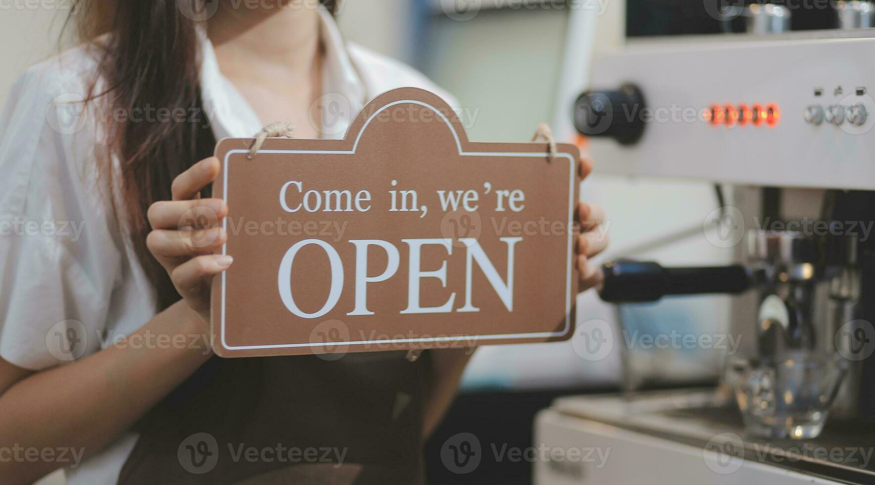 Young entrepreneur holding open sign on glass door at cafe photo