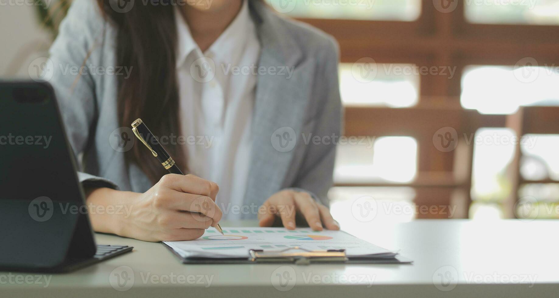 Asian Business woman using calculator and laptop for doing math finance on an office desk, tax, report, accounting, statistics, and analytical research concept photo