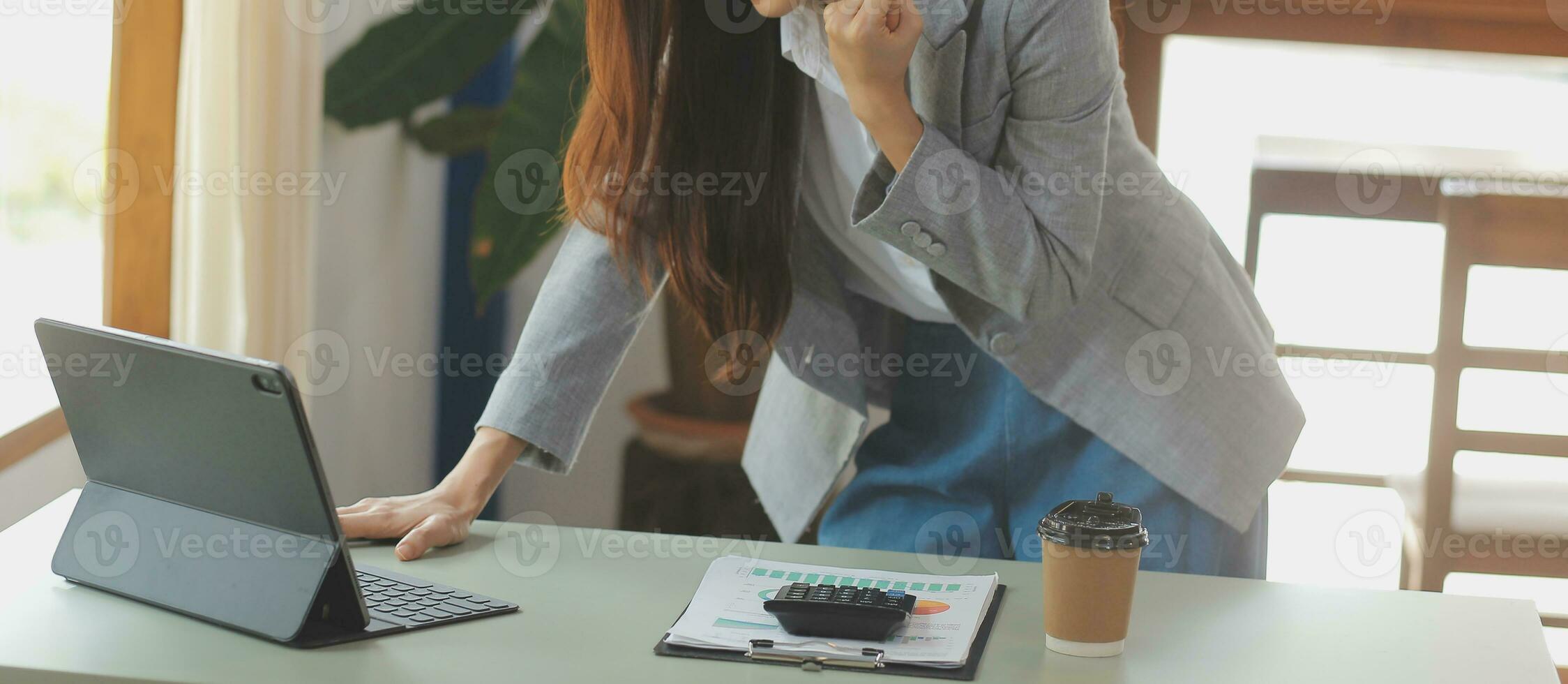 Asian Business woman using calculator and laptop for doing math finance on an office desk, tax, report, accounting, statistics, and analytical research concept photo