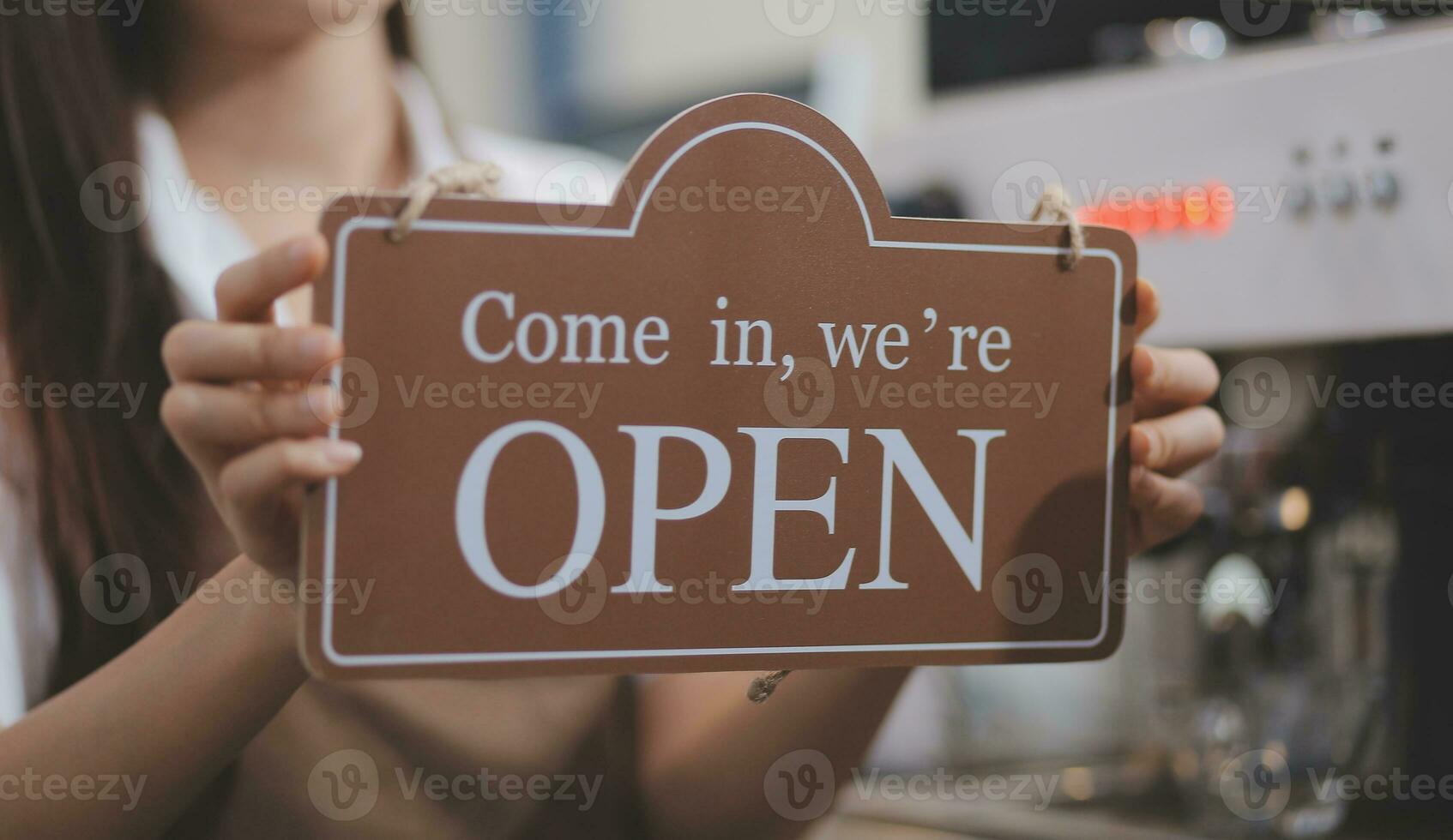 Welcome. Open. barista, waitress woman turning open sign board on glass door in modern cafe coffee shop ready to service, cafe restaurant, retail store, small business owner, food and drink concept photo
